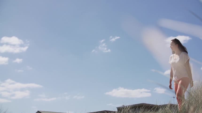 Woman walks in front of a sunny blue sky