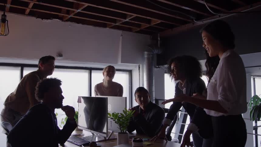 Group of people attends a meeting in an office while a woman presents ideas