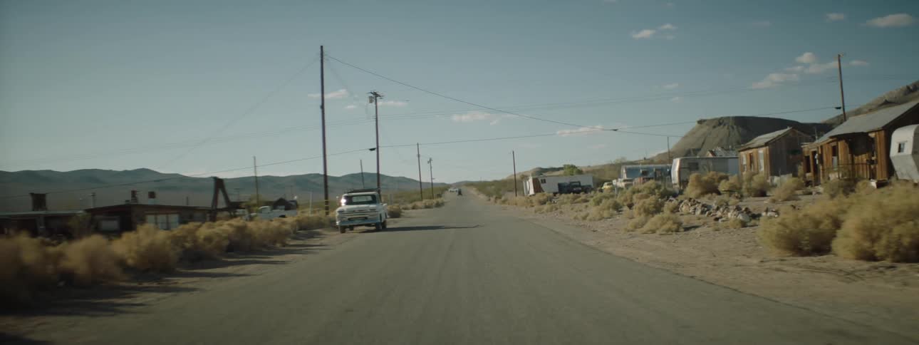 Pickup trucks trailers and small houses along a stretch of rural road