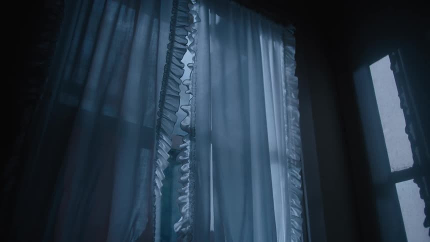 Lights shine in through a curtained window