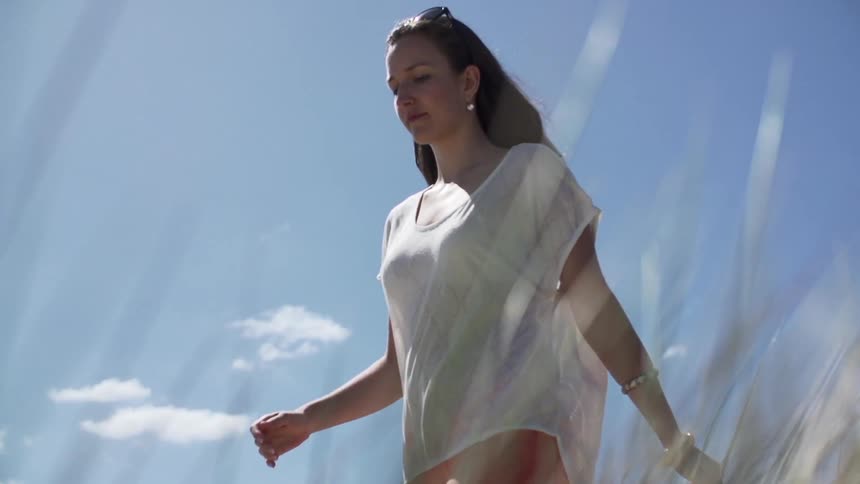 A woman walking under a partially cloudy sky