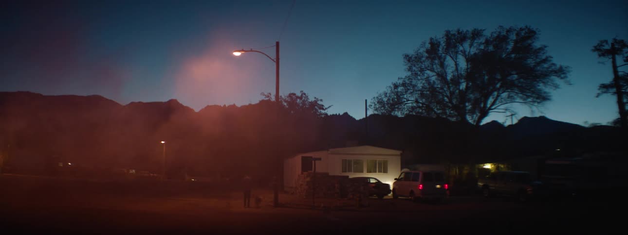 A view of a house and a street light with some smoke rolling through