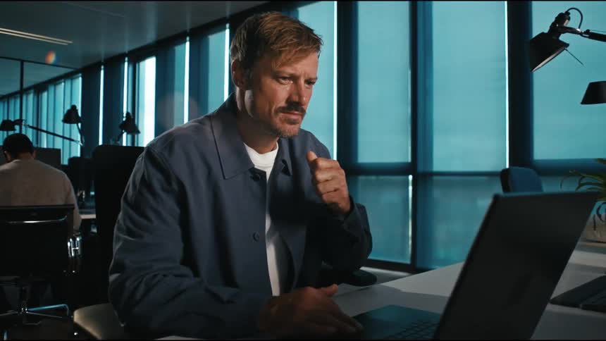 In a sleek modern office a focused man works intently on his laptop