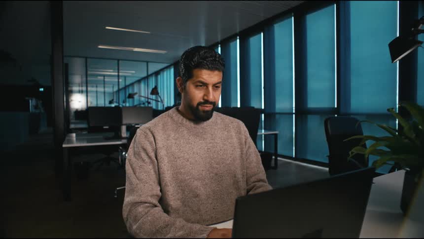 push in on a man working in the office, he is focussed and satisfied with the work