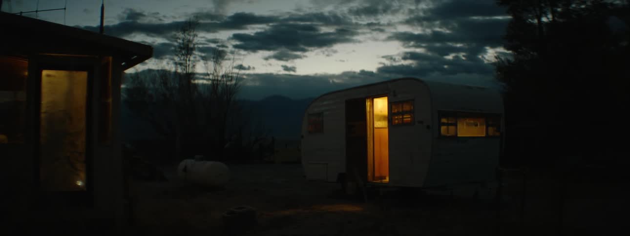 Light shines from a small camper at night