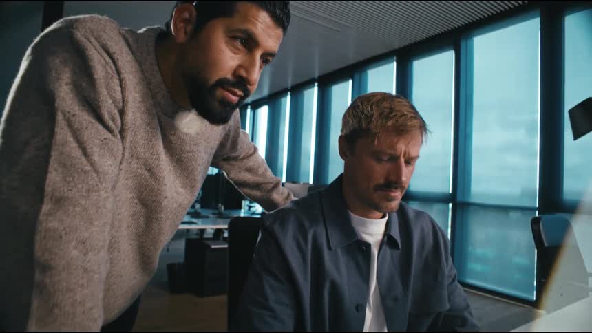 two colleagues working at a computer, one points at the screen and they nod