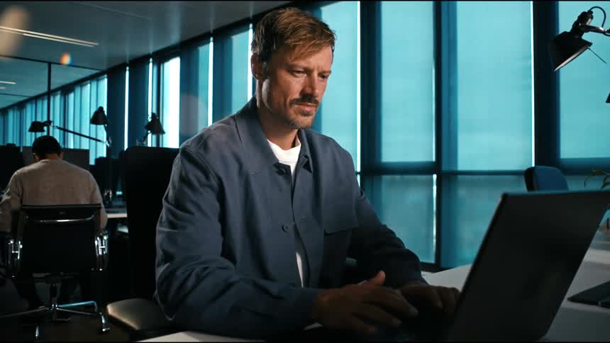 slow push in on a man typing concentrated and focussed on his laptop