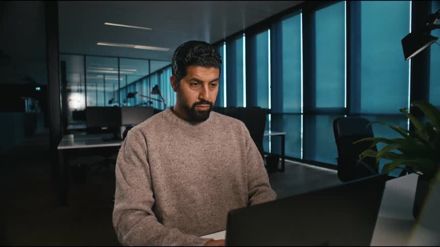 slow push in on a man working concentrated in the office