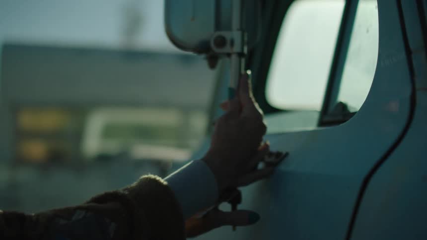 A woman rubbing a truck trying to find the door