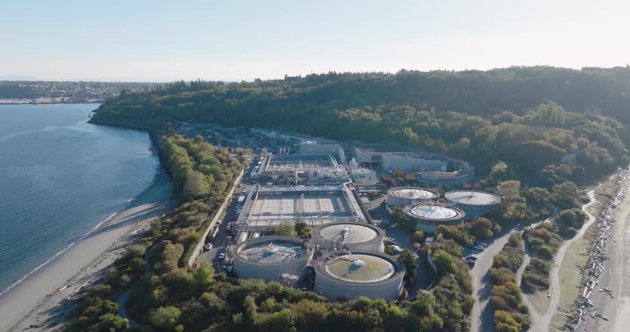 Orbit around a wastewater treatment plant complex surrounded by woods and coastal waters
