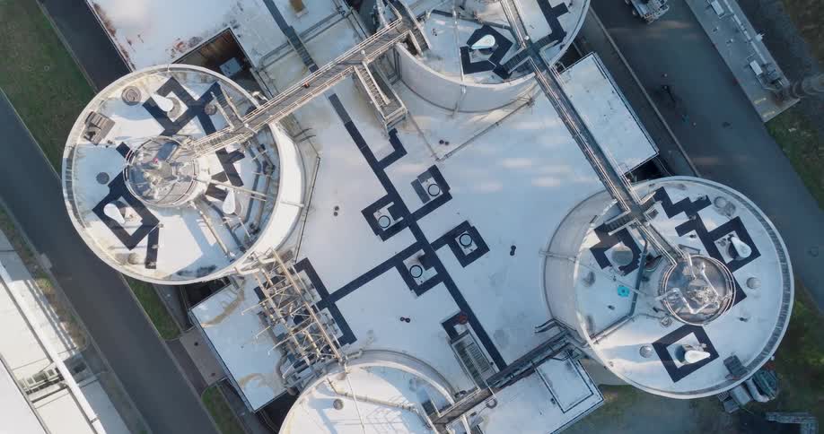 Twisting ascent over circular tanks connected by walkways and piping at a wastewater treatment facility