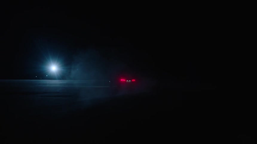A car drives towards a bright light at night