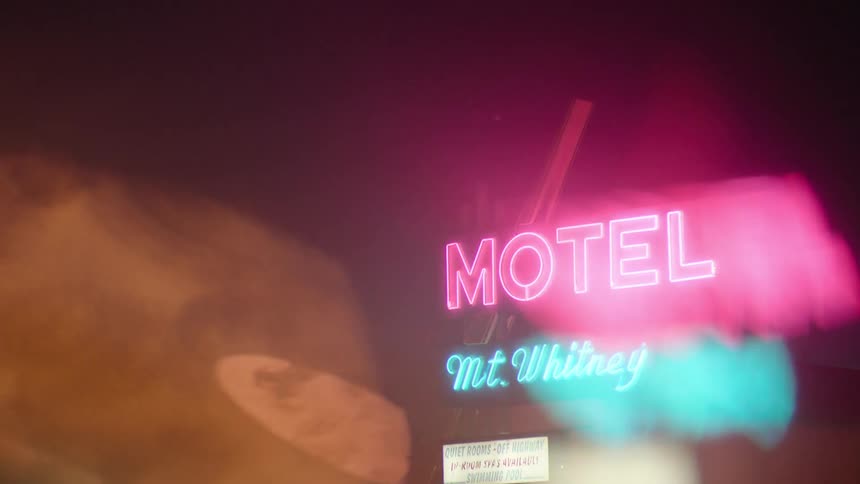 A motel sign shines in the dark night