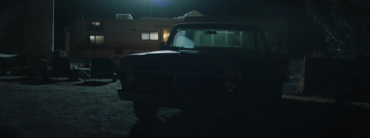 Lights flicker behind a parked pickup truck at night