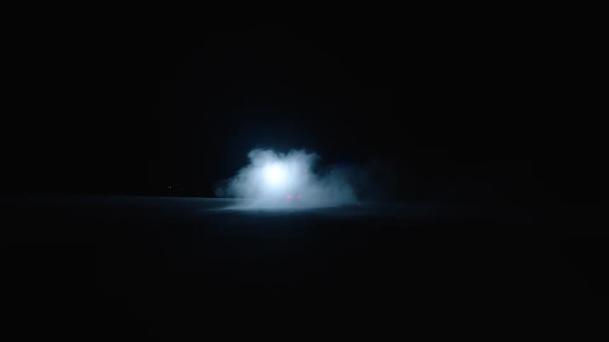 A car drifts and speeds away leaving a trail of exhaust