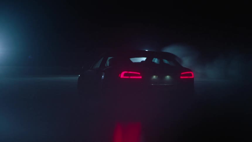Sports car driving fast at night while bright lights shine in the distance