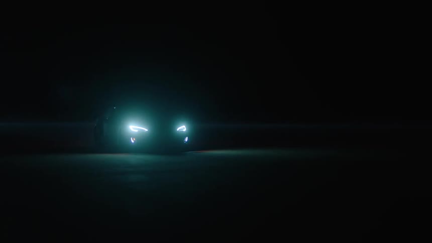 A car drives at night with its headlights on