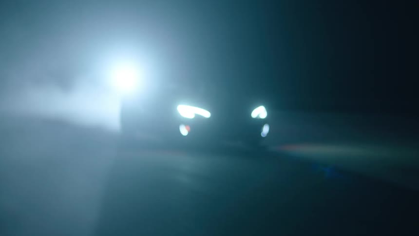 A car drives at night with its headlights on