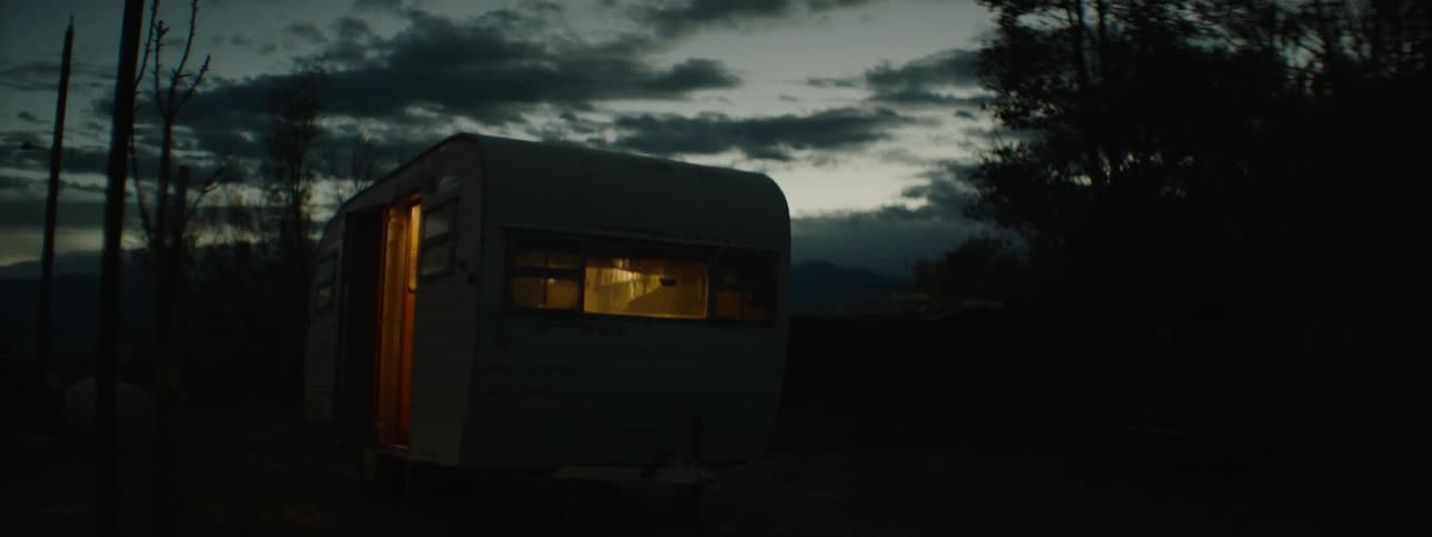Lights shine from within a small camper at night