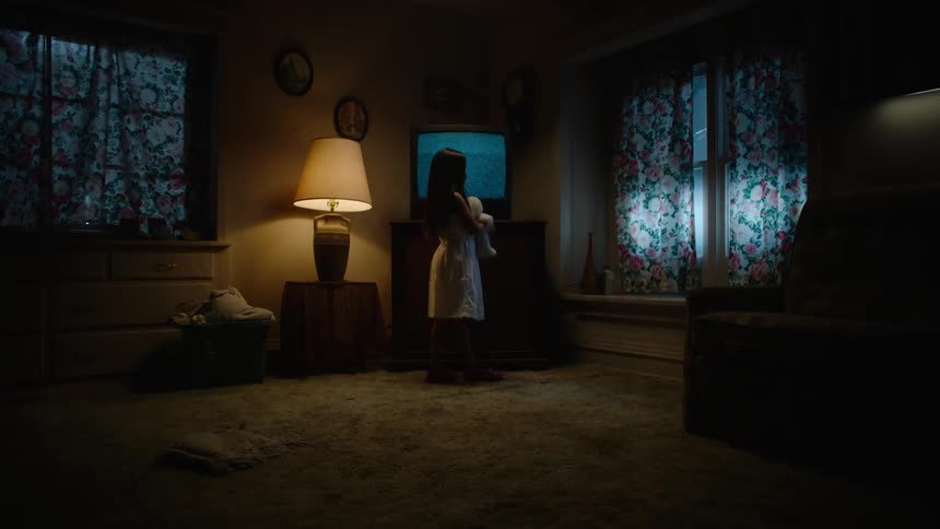 A child standing in a living room in front of a staticky television