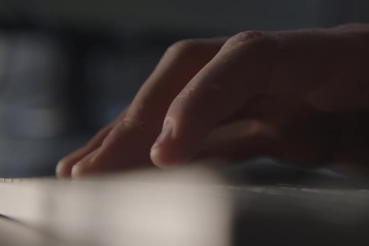 Male hand pressing a key on a keyboard indoors