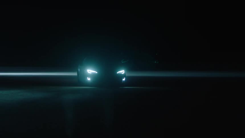 A car drives at night with its headlights on