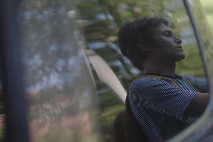 Man reflected in the window of a moving vehicle under natural light