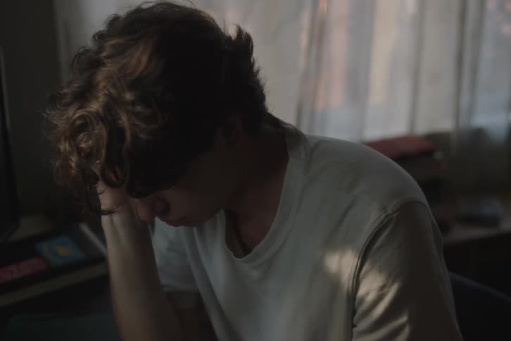 The teenager is sad as he sits in the room