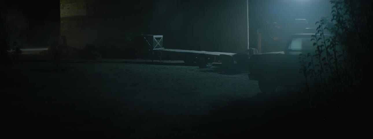 An old pickup truck is parked outside at night