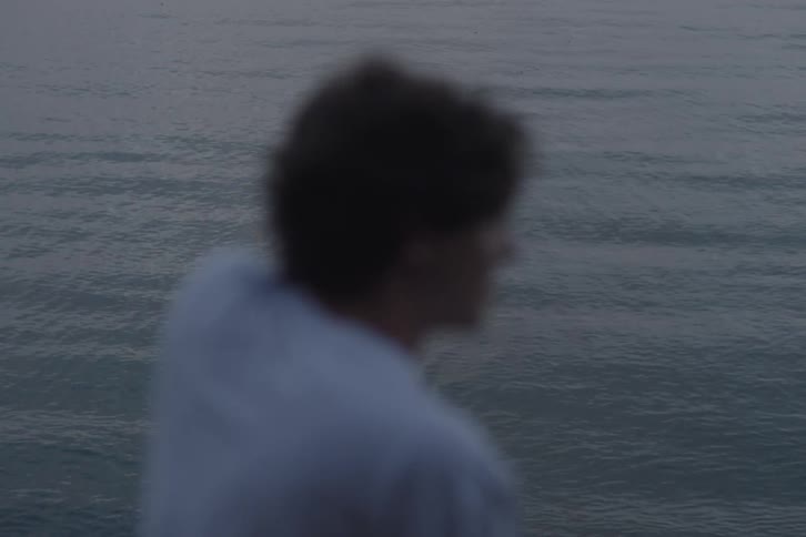 Blurred man gazing at the sea at dusk