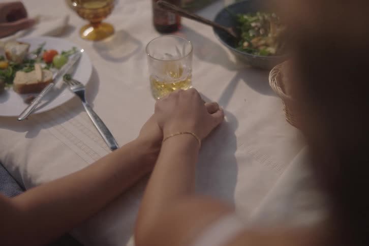 Couple sitting at the dinner table holding hands before the meal