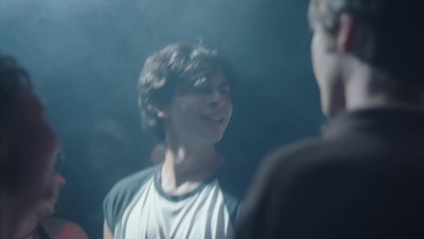 Small group of female and male teenagers dancing and jumping at a party on a club indoors