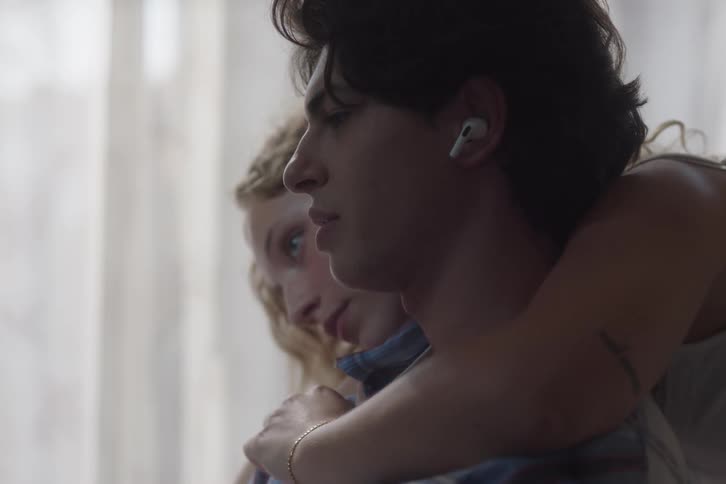 Woman hugging man while he wears earphones