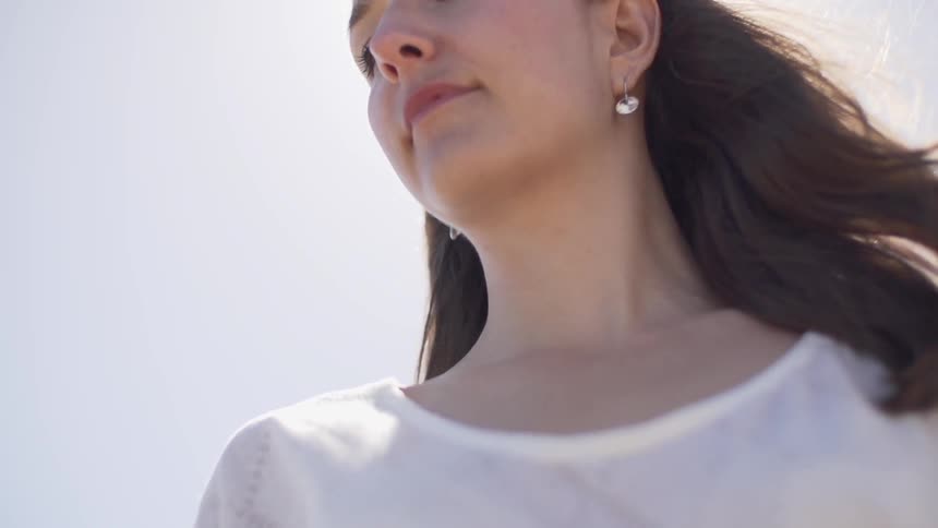 A woman stands outside on a sunny day