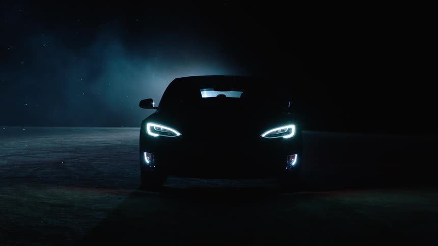A car with its headlights on sitting in a dark parking lot
