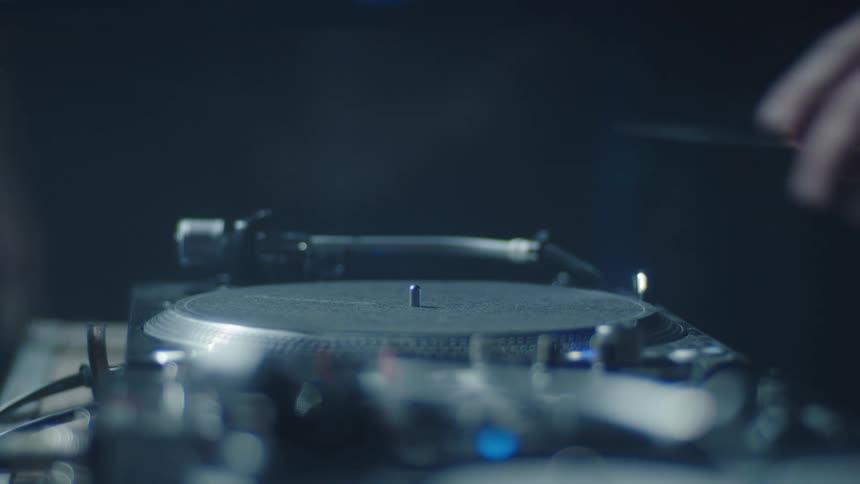 Hands adjusting the turntable during a dj performance