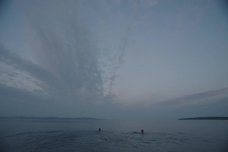 Two people run and swim in the water of the beach