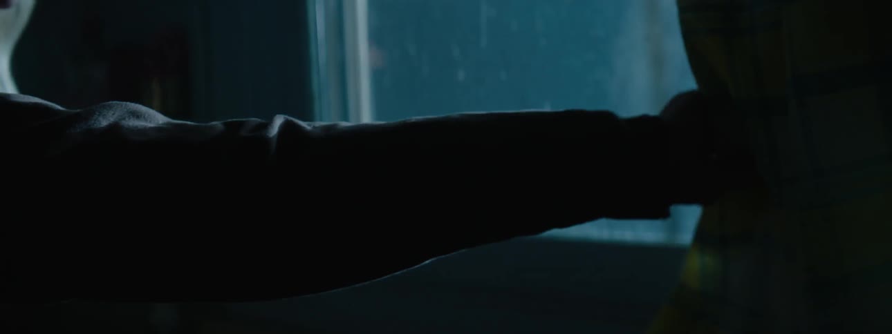 An older woman with gray hair looks out a window toward flashing lights