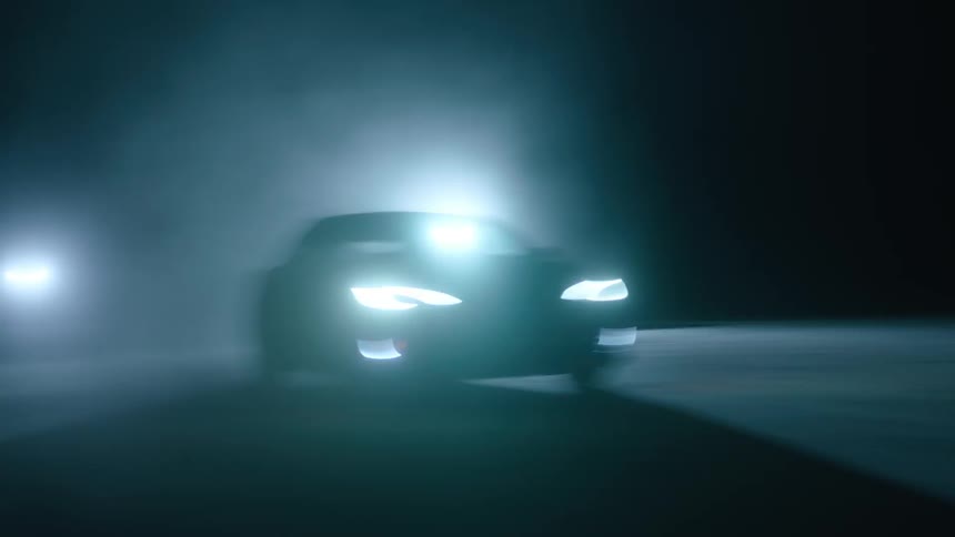 A car drives with its headlights on at night