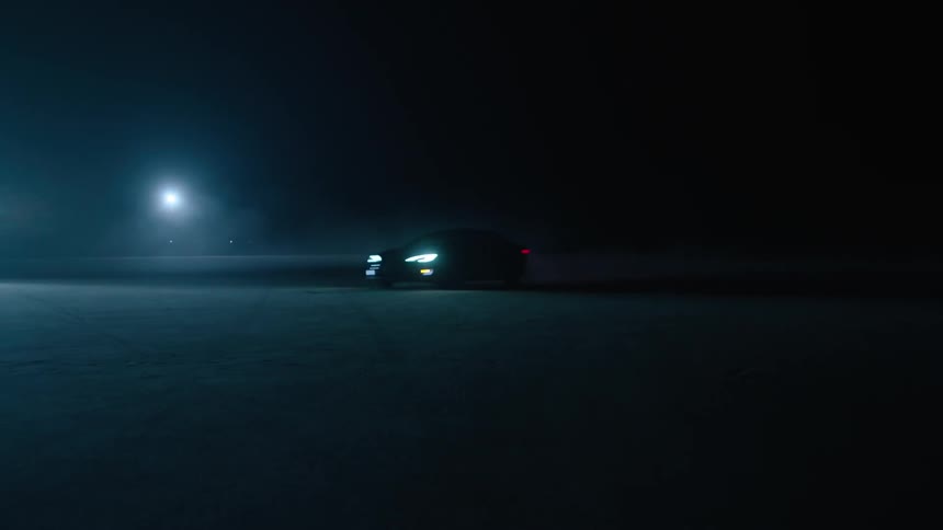 A car drives at night with its headlights on