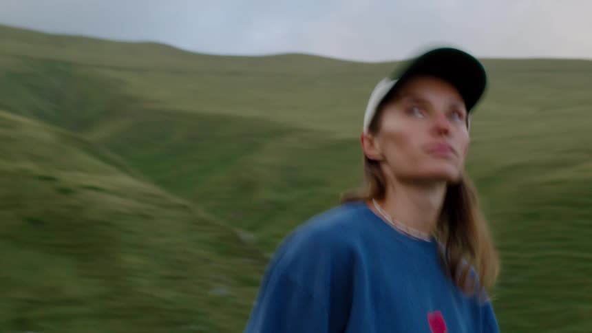 Woman wearing a cap and blue sweatshirt in a mountainous area