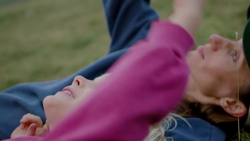 A mother and son relax on the grass sharing a joyful moment outdoors
