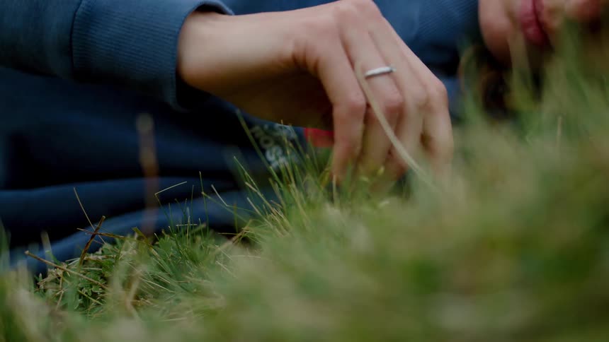Person lying on the grass touching the ground with their hand
