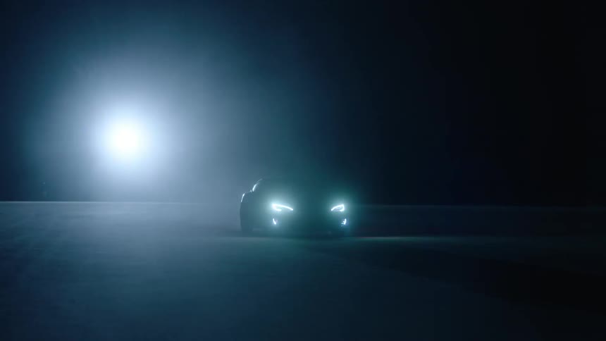 A car drives at night with its headlights on
