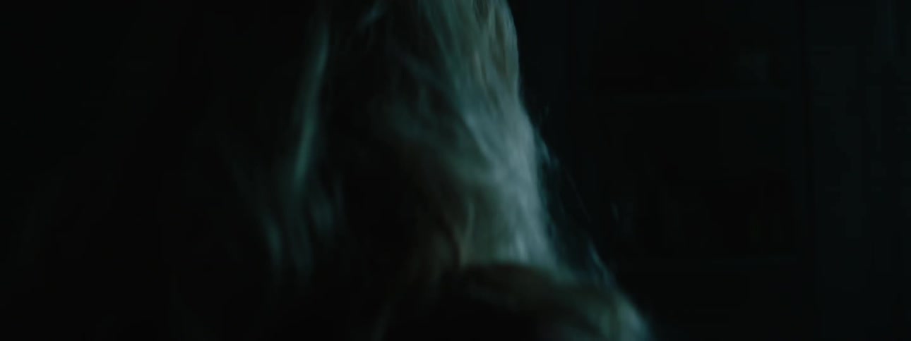 An elder woman with blonde hair looking around in a dark space