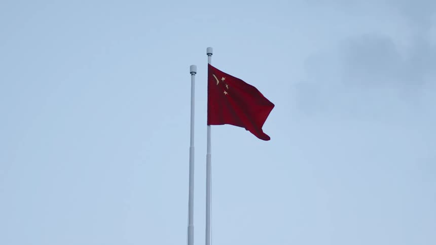 Flag of china waves in the wind under a clear blue sky