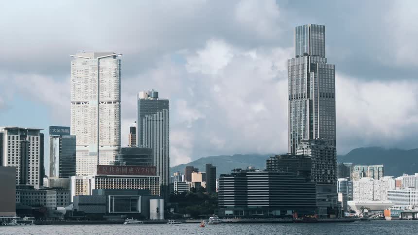 Cluster of modern skyscrapers by the waterfront with mountains in the background in hong kong