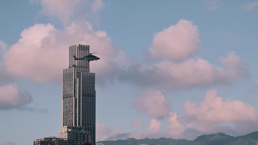 Helicopter flying over hong kong skyscrapers under a blue sky with pink clouds