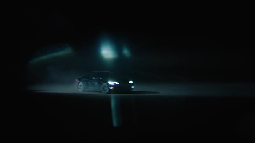 A car drives at night with its headlights on