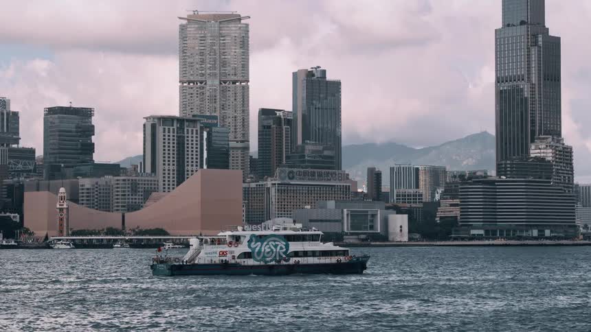 Boat sailing near modern buildings with mountains in the background